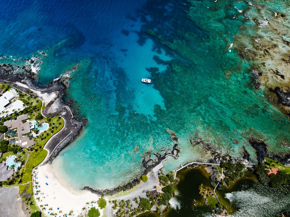 Vista aérea de una playa privada en Mauna Lani con aguas turquesa y arrecifes
