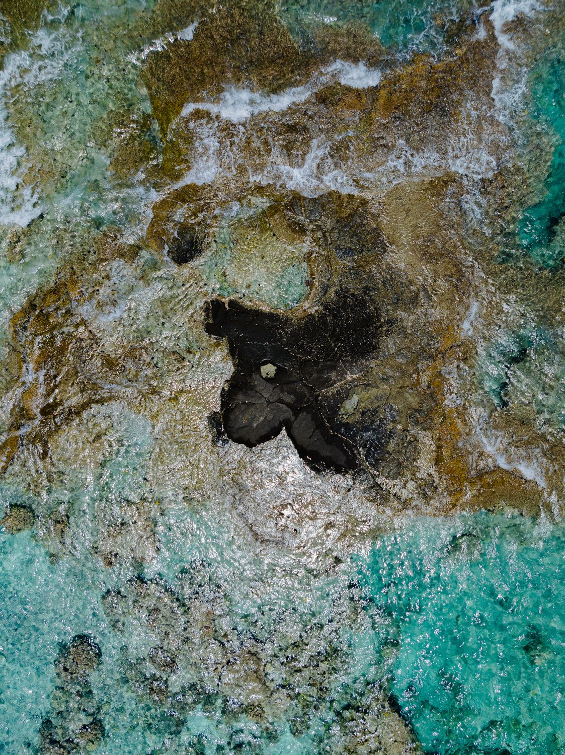 A small black rock in the middle of the ocean · Free Stock Photo
