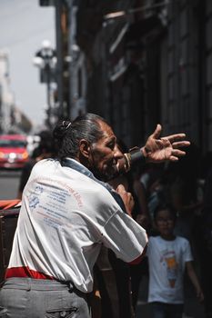 A man passionately gestures while performing on the bustling streets of Puebla, Mexico.