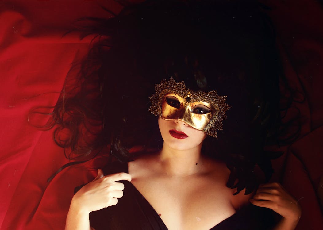 Free Woman Laying On Red Textile Wearing Gold Mask Stock Photo