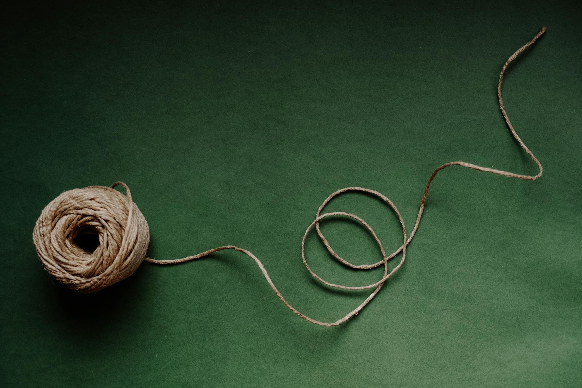 A ball of twine on a green surface creating a minimalist still life composition perfect for design projects.