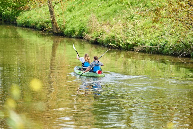 Back View Of A Couple Kayaking In A River