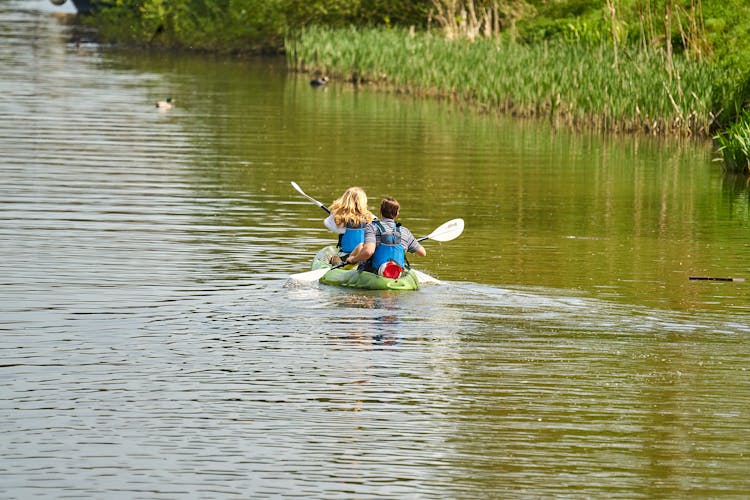 Back View Of A Couple Kayaking In A River