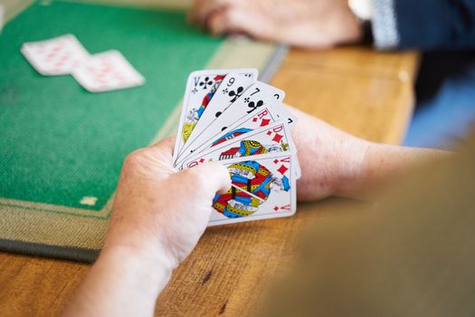 Detailed view of hands holding playing cards during a casual indoor card game session.
