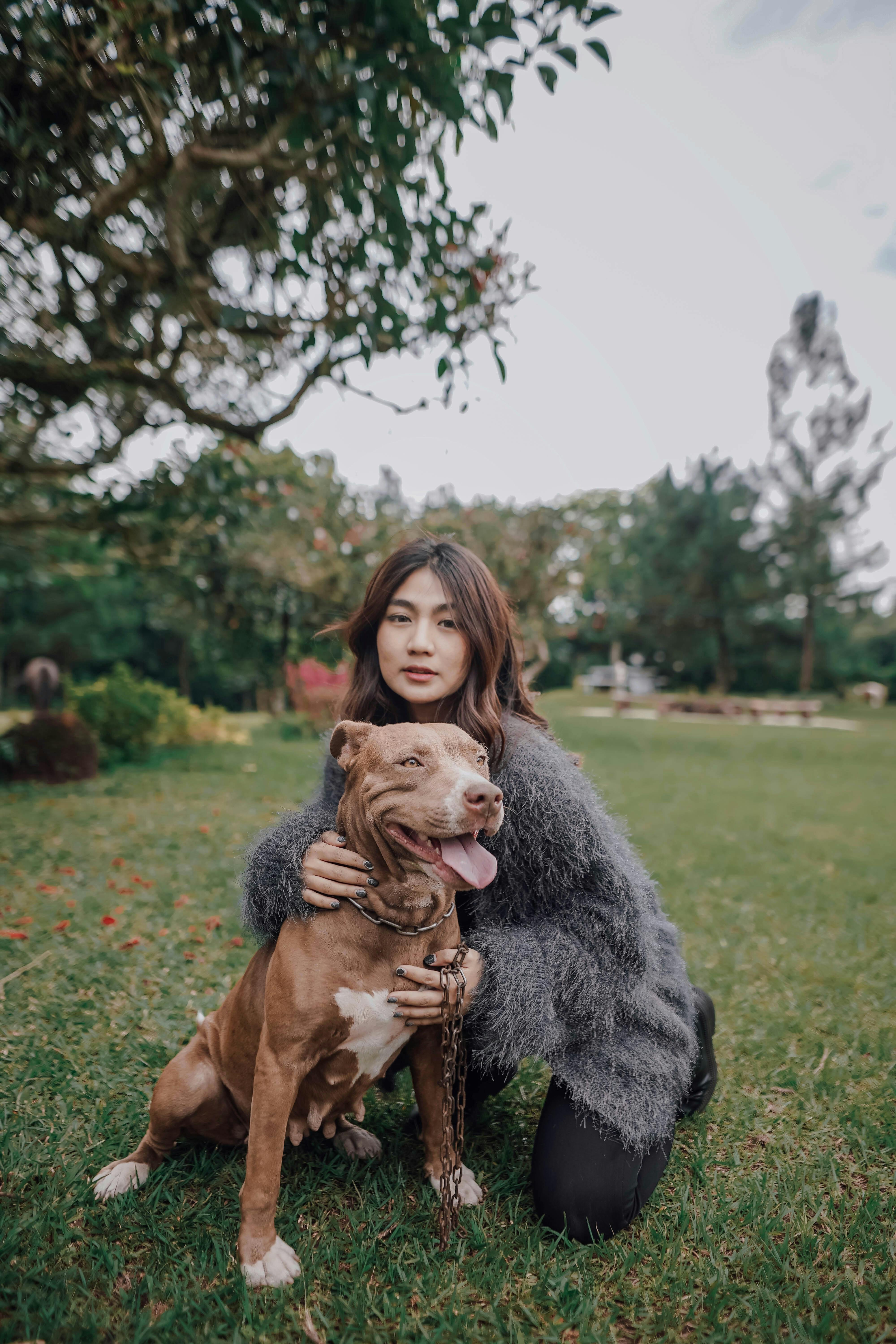A woman lovingly embraces her dog in a beautiful park setting in Indonesia.