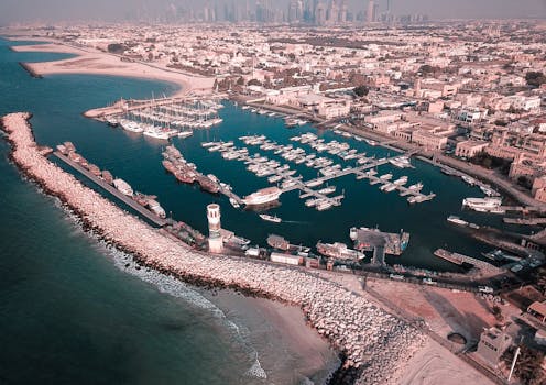 Aerial drone shot capturing a picturesque harbor with boats and a beachfront cityscape.