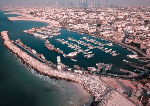 Free Aerial drone shot capturing a picturesque harbor with boats and a beachfront cityscape. Stock Photo
