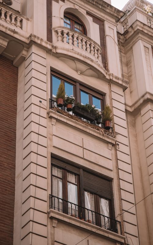 Free Elegant urban building facade in Valencia with plants on balcony, showcasing Spanish architecture. Stock Photo