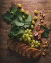 一幅描绘木桌上葡萄、切片面包、无花果和核桃的乡村静物画