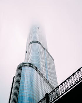 低角度镜头中，一座现代摩天大楼消失在雾蒙蒙的天空里，突显了城市建筑的宏伟