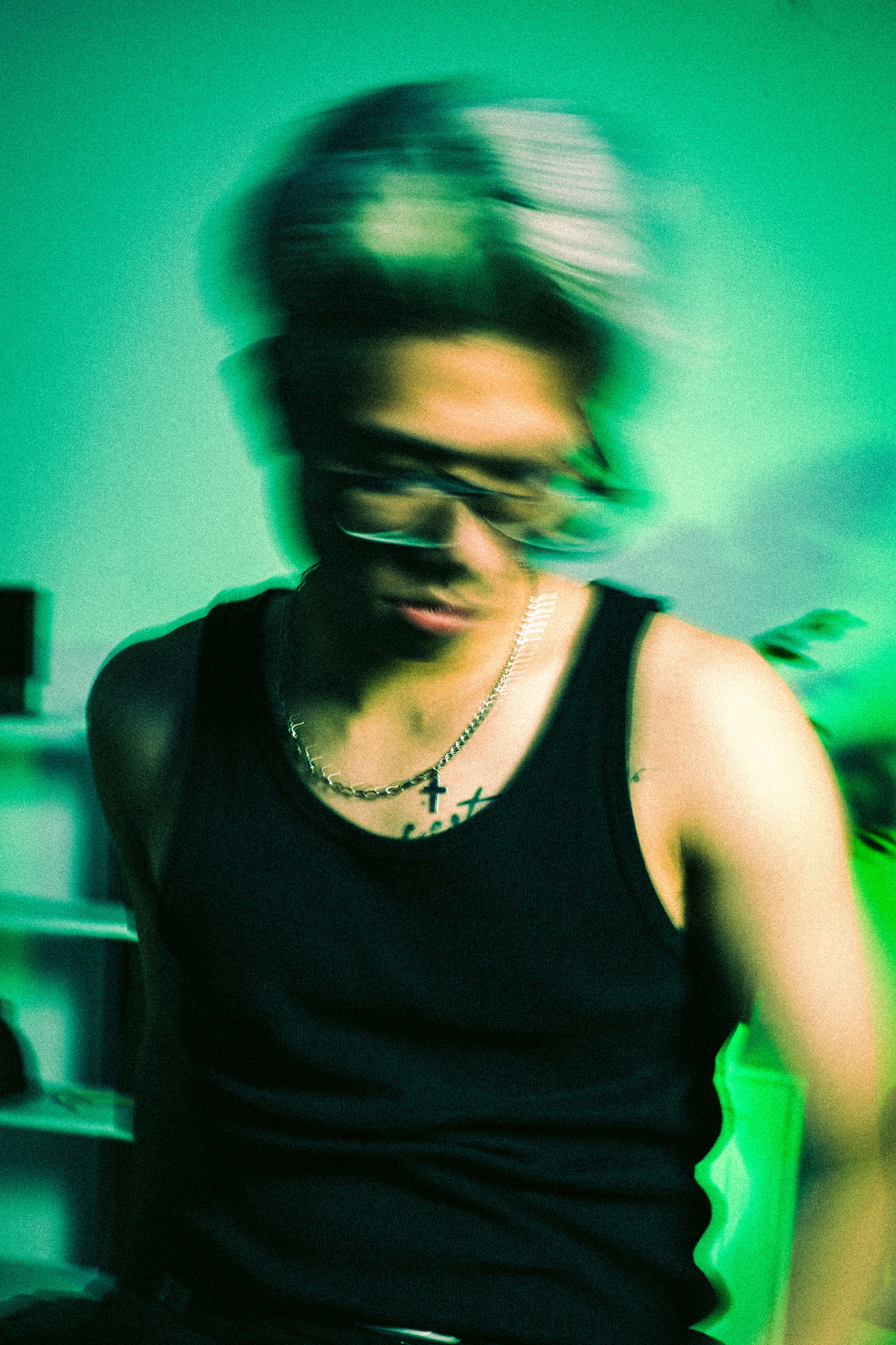 Blurred portrait of a young man in a studio setting, evoking energy and movement.