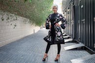 一位身穿花卉长袍、头戴头巾的时尚女子，在户外自信地摆着姿势