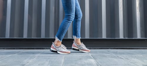 Person Walking Beside Gray Wall