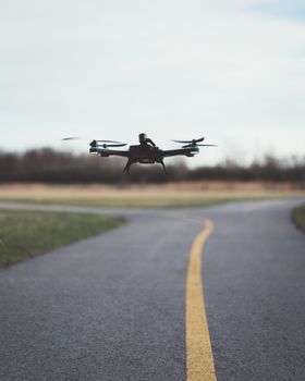 Aerial drone flying low close to a winding road surrounded by grass.