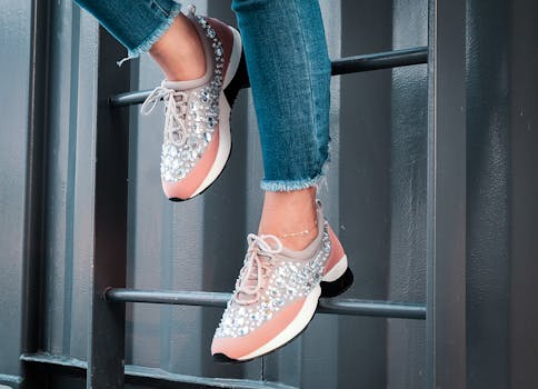 Close-up of a person's legs in blue jeans and embellished sneakers on a metal ladder.