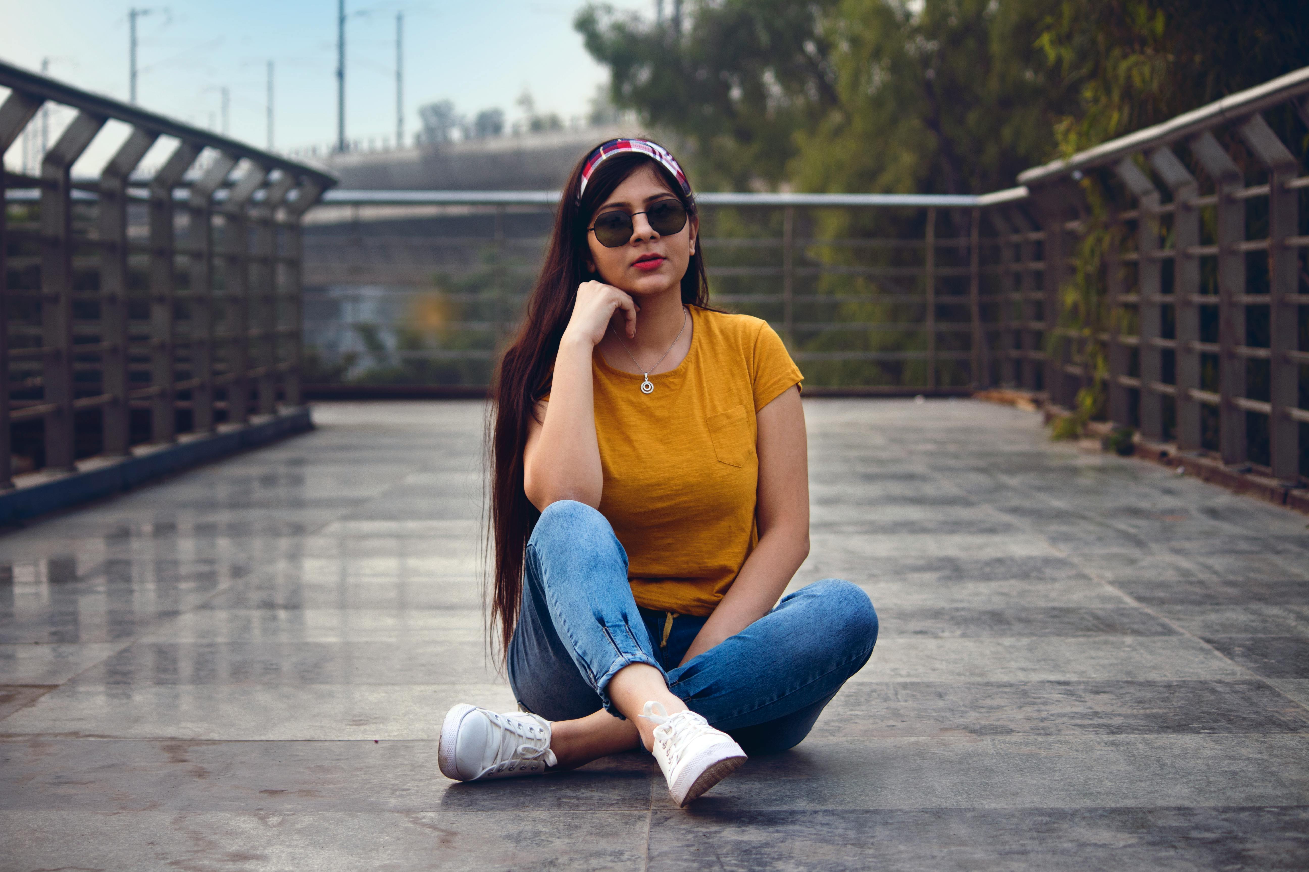 A beautiful dark-haired girl in blue jeans sits in a lotus pose on the  grass in a pine forest. Stock Photo | Adobe Stock