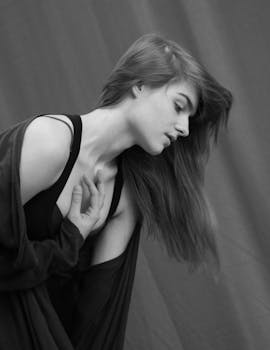 Black and white portrait of a woman posing gracefully against a curtain backdrop.