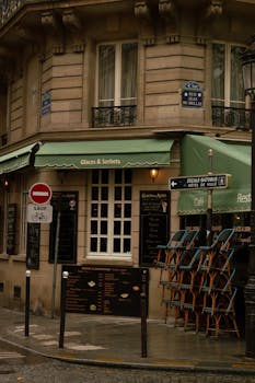 Cozy Parisian café corner on a rainy day, showcasing stacked chairs and a quaint atmosphere.