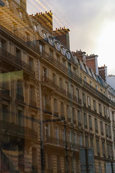 Elegant Parisian building facade with window reflections captured at sunset.