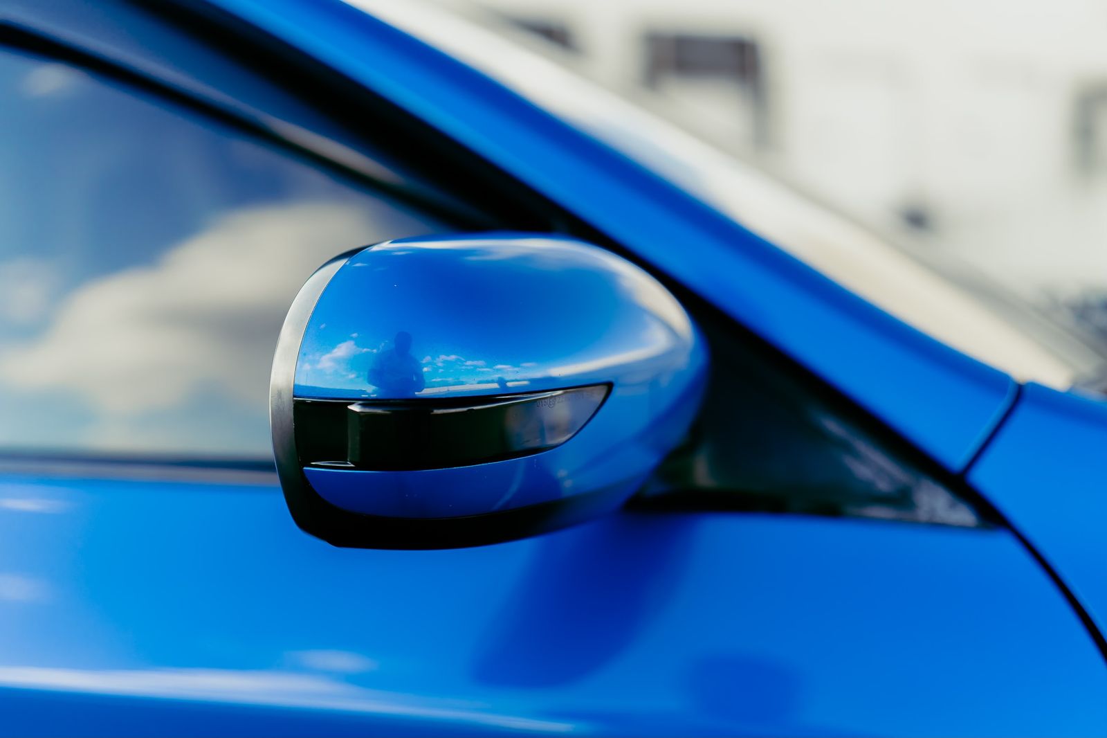 Wing mirror of a blue car reflecting open sky — photo by Garvin St. Villier on Pexels