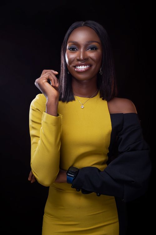 Free Portrait of a smiling woman in a fashionable yellow and black dress against a dark background. Stock Photo