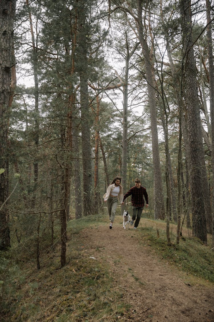 Woman And Man Running With Dog In Forest