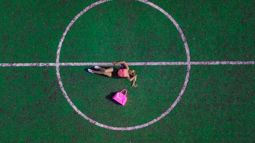Woman Lying on Field Beside Pink Bag