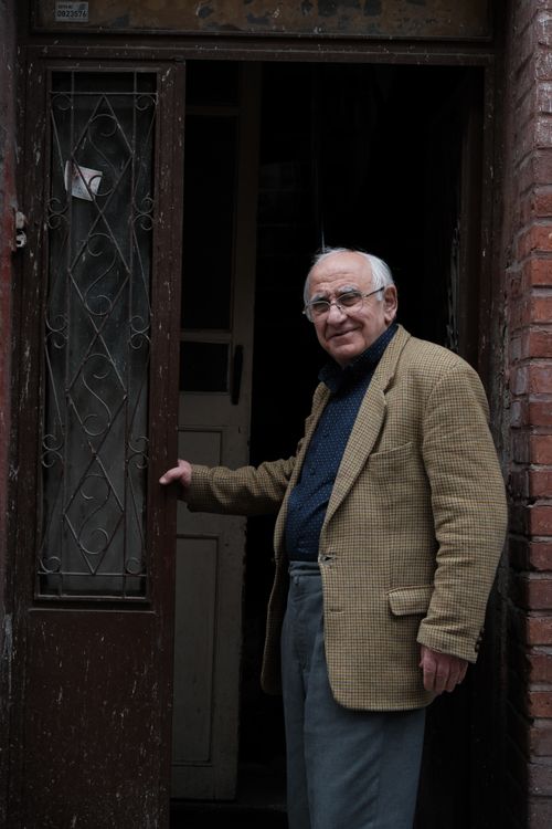 Free Senior man in a classic outfit standing in an old doorway, adding historical charm. Stock Photo
