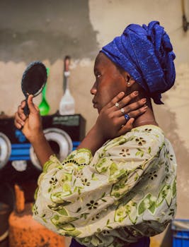 Black woman holding mirror in Nigerian traditional attire, Port Harcourt.