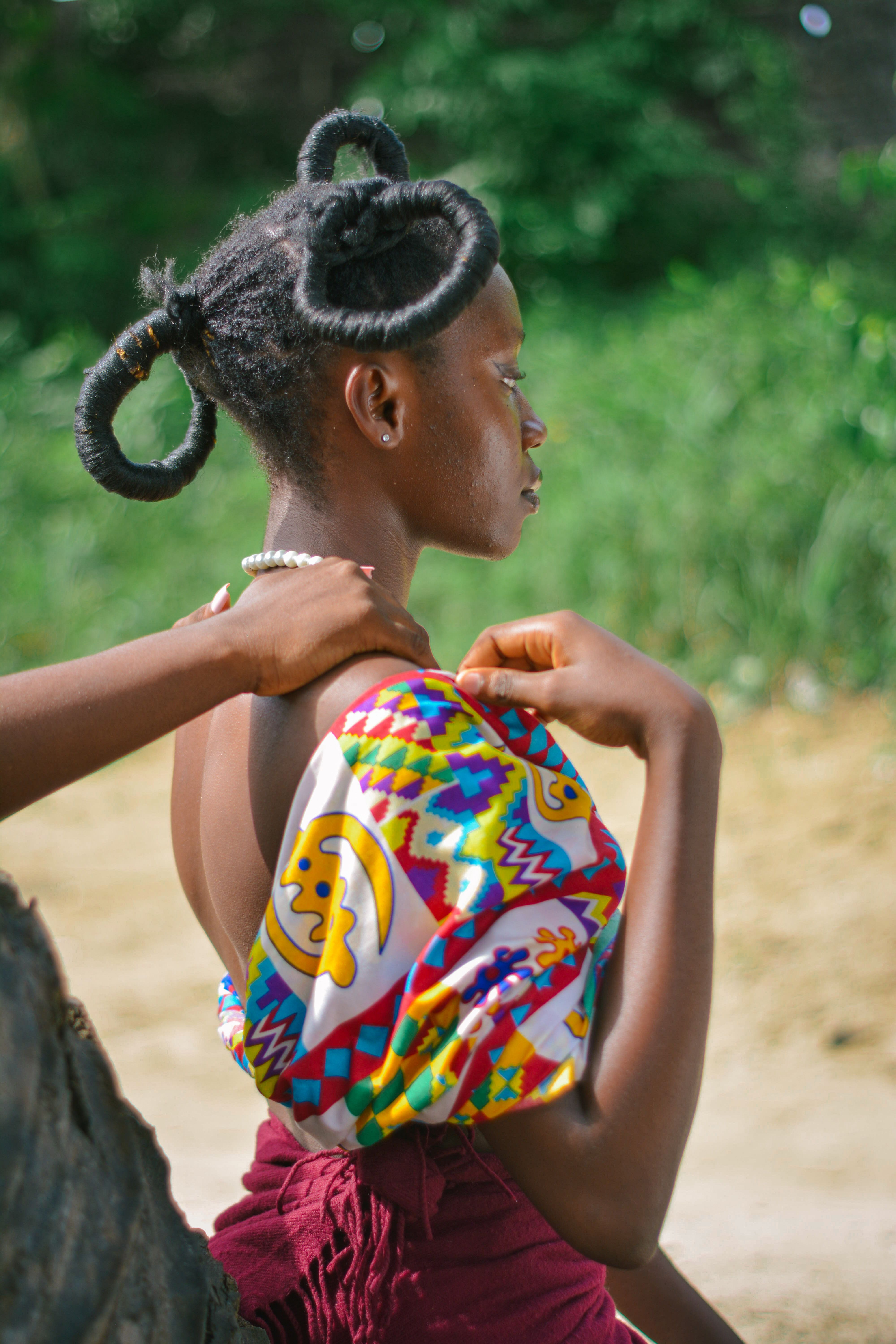 A portrait of a young woman outdoors in vibrant traditional attire enjoying peaceful relaxation.