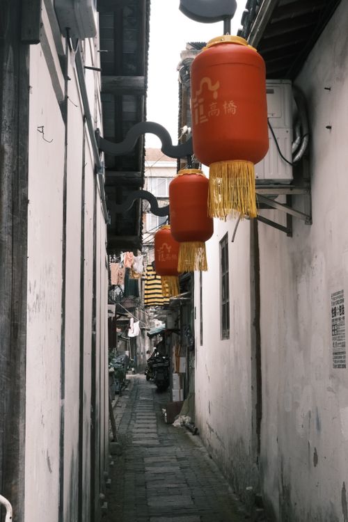 Free A narrow urban alleyway with hanging red lanterns in an Asian city, showcasing cultural architecture. Stock Photo