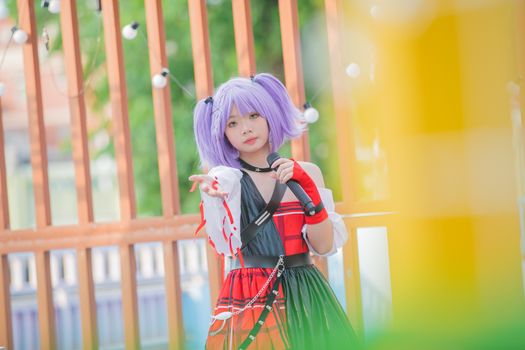Vibrant cosplay portrait of a young woman with purple hair outdoors.