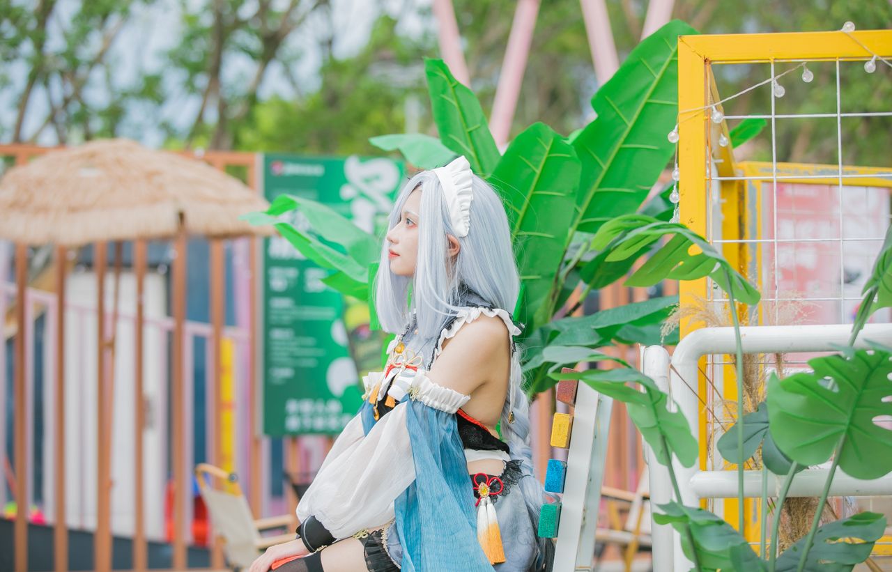cosplayer in colorful costume sitting outdoors with lush green leaves
