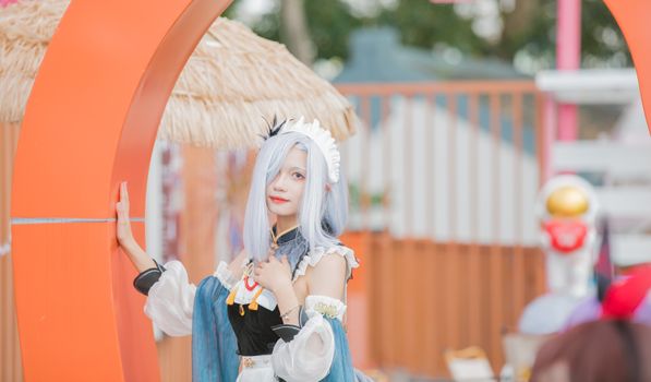 Young woman in vibrant cosplay costume poses outdoors with a playful expression.