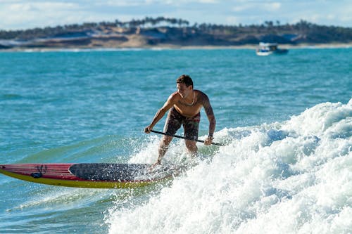 Free Man Surfing On Water Waves Near Island Stock Photo