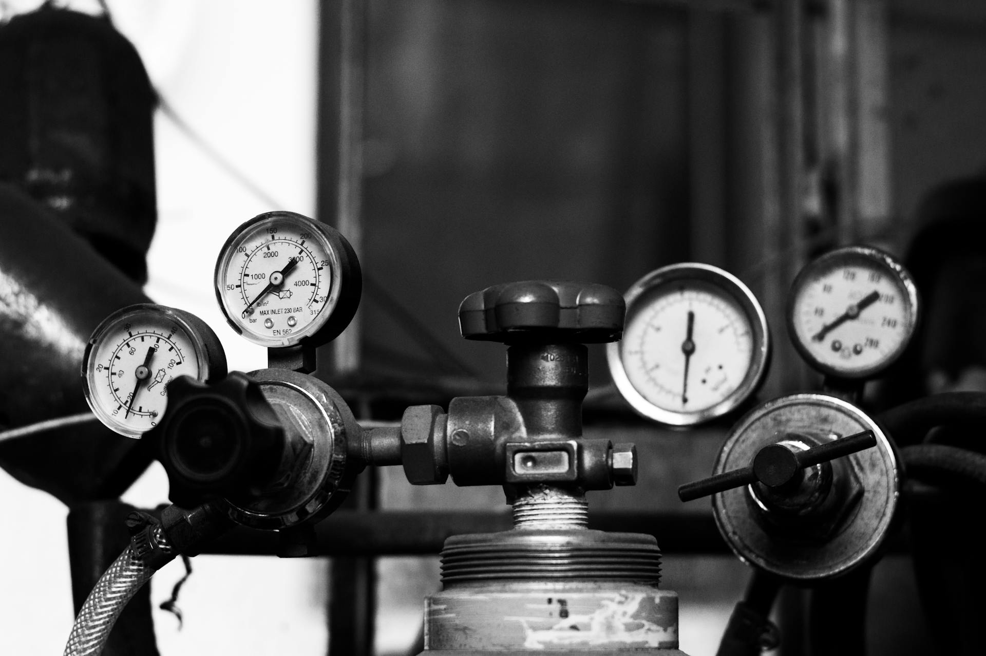 Black and white photo of vintage industrial pressure gauges and valves displaying precision mechanics.