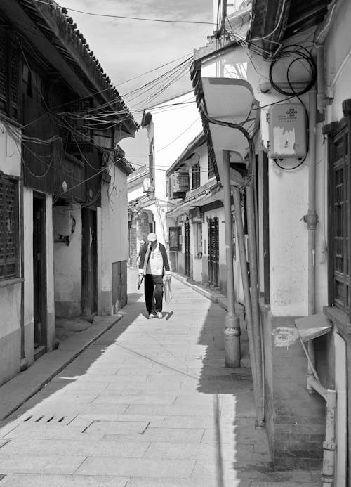 Man on Sunlit, Narrow Street in Town