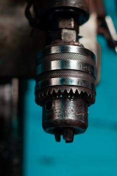 Industrial drill chuck in focus with blue background showcasing metal details.