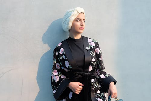 Woman in Black and Pink Floral Robe Leaning on Wall