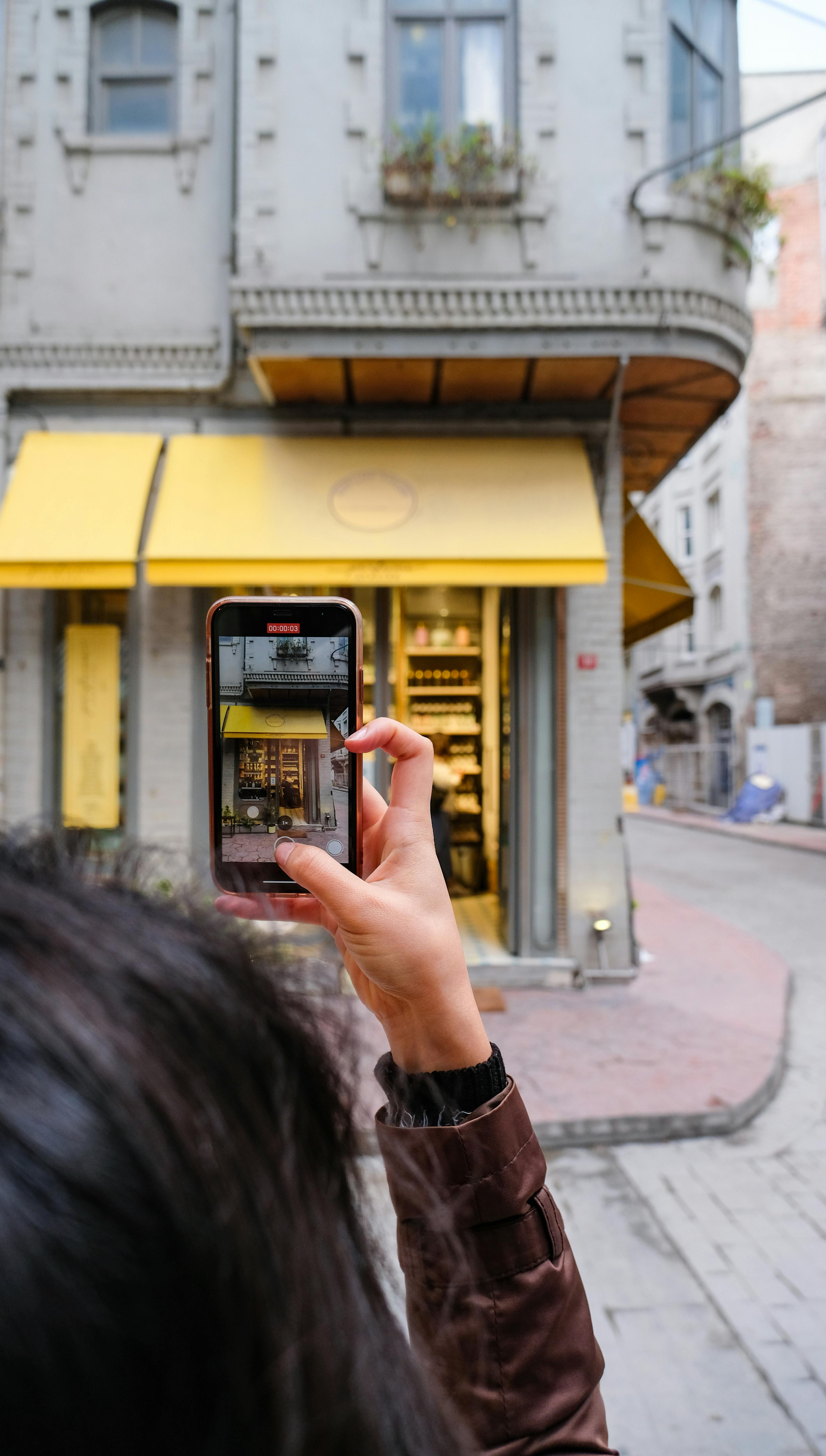 A person photographing a historic urban building with a smartphone on a city street.