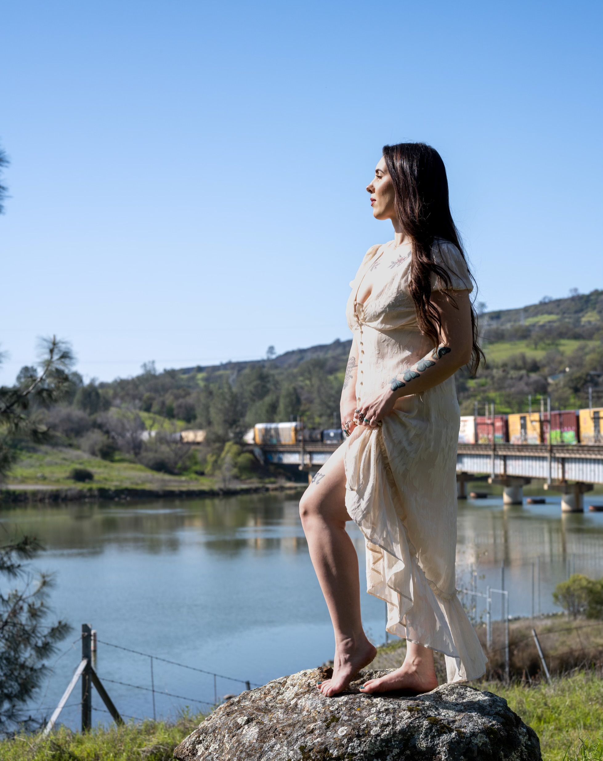 Young Woman in a Dress Standing on a Rock by the Water · Free Stock Photo