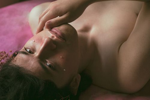 Free An artistic portrait of a topless man lying down, hand on chin, evoking a sense of introspection. Stock Photo