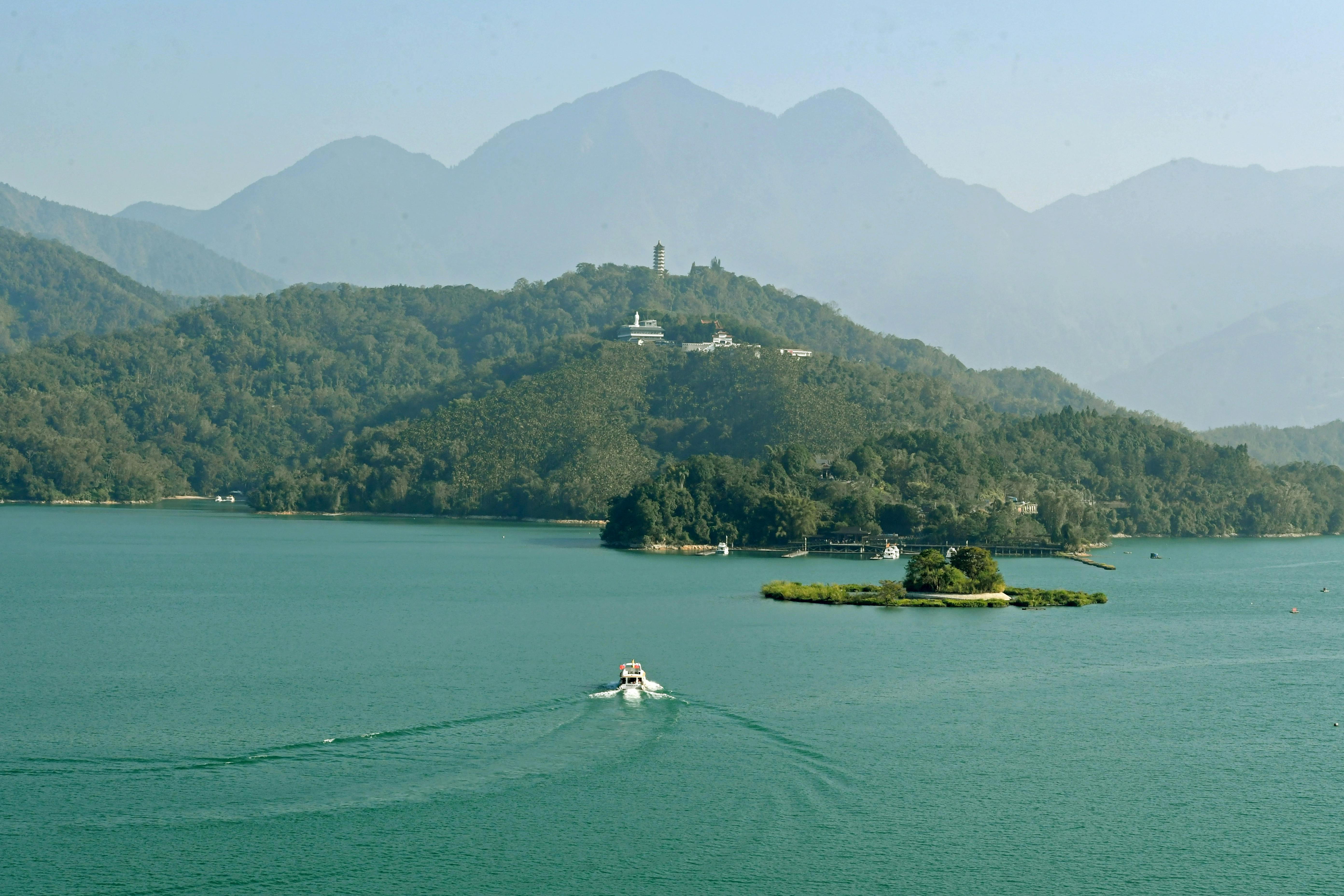 A picturesque aerial view of a boat on Sun Moon Lake surrounded by lush hills in Taiwan.