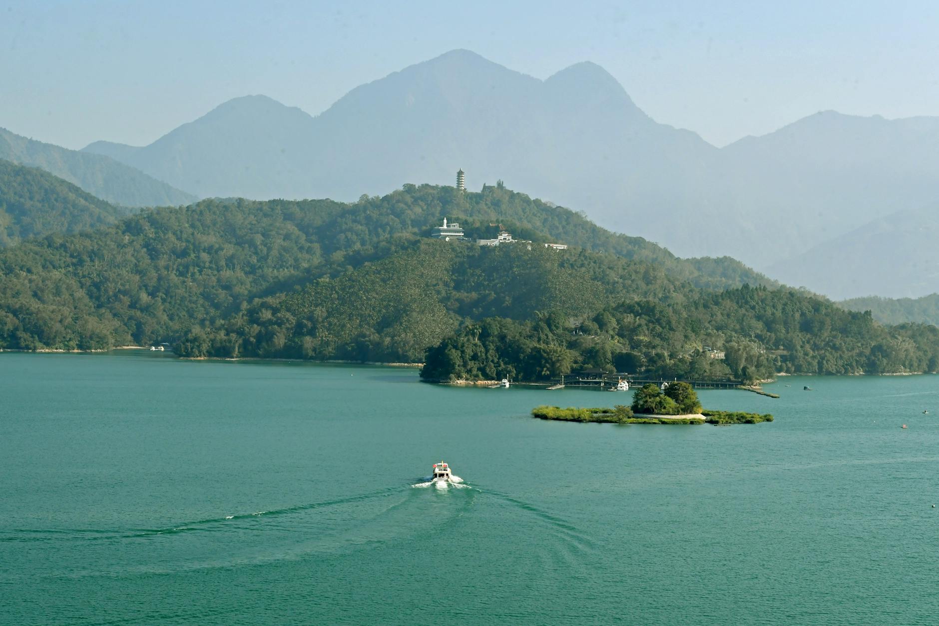 A picturesque aerial view of a boat on Sun Moon Lake surrounded by lush hills in Taiwan.