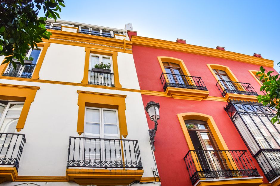 Fachada arquitectónica vibrante en Sevilla, España, que muestra balcones tradicionales y colores brillantes.