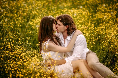 Free A couple sharing a romantic kiss in a vibrant yellow meadow during daylight. Stock Photo
