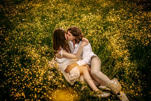 Free A couple embracing lovingly amidst a vibrant field of yellow flowers, capturing a moment of romance. Stock Photo
