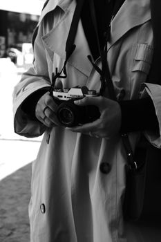 Black and white photo of a woman elegantly holding a classic camera, showcasing fashion and photography.