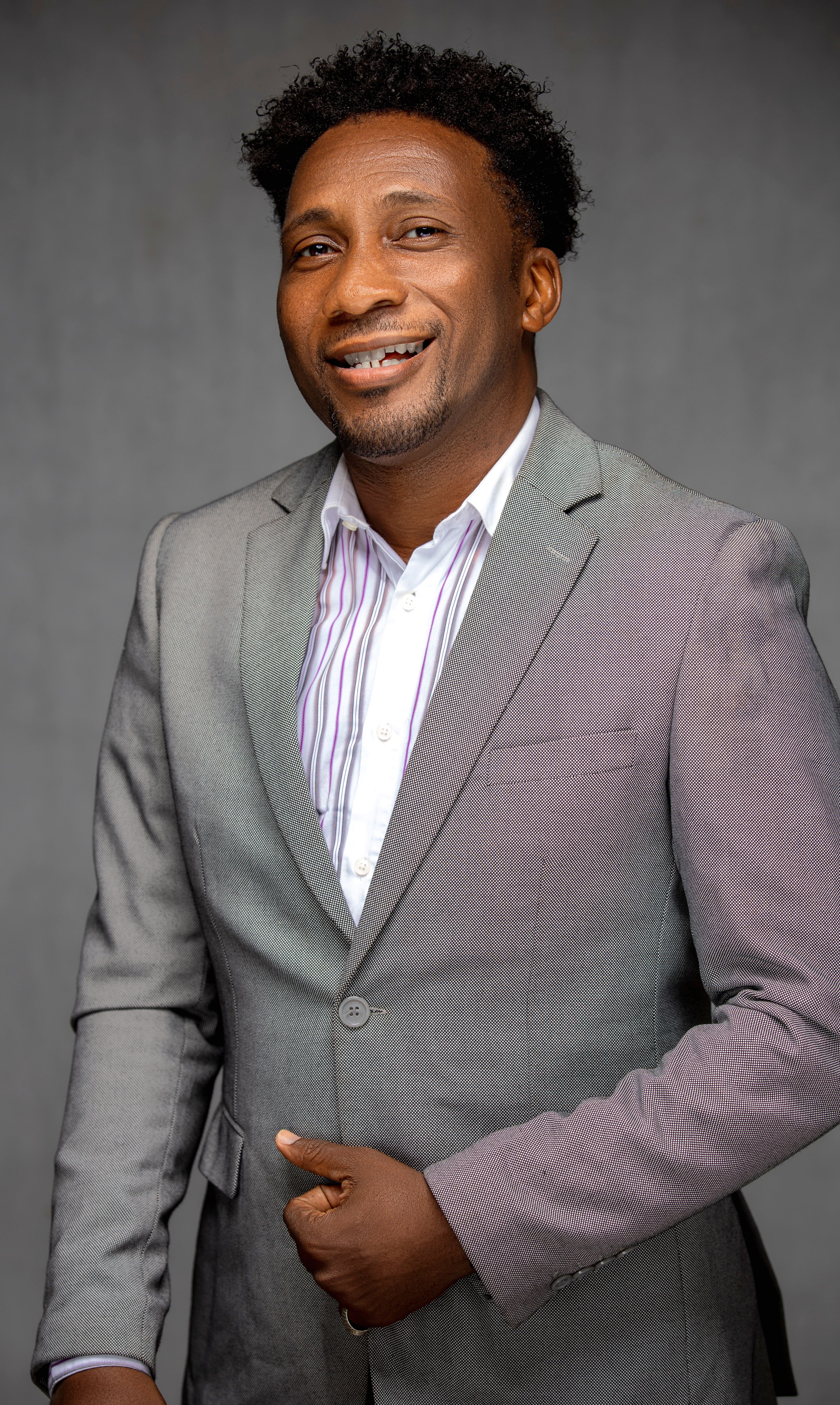 Portrait of a confident mid-adult man in a gray suit with a friendly expression.