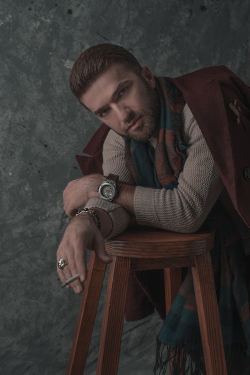 Photo of Stylish Man Leaning on Stool While Smoking